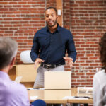 businessman-standing-and-leading-office-meeting-ar-YJFNZHB-1024x683