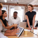 businesspeople-meeting-around-table-in-modern-offi-PYML4WH